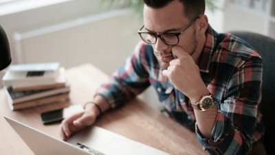 Man looking at his laptop while hands on chin