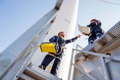Electric engineer wearing Personal protective equipment working at wind turbines farm