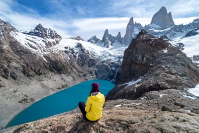 A Hiker With A Yellow Jacket Sitting On The Base Of El Chalten Mountain In Argentina	