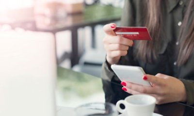 Close up photograph of a woman holding a card on one hand and a smartphone on the other hand.