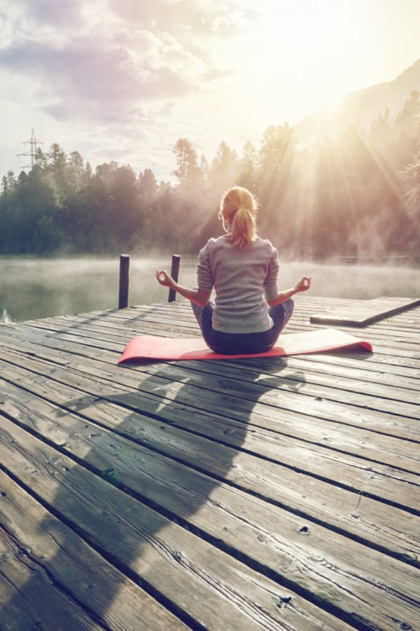 Girl meditating along the lake