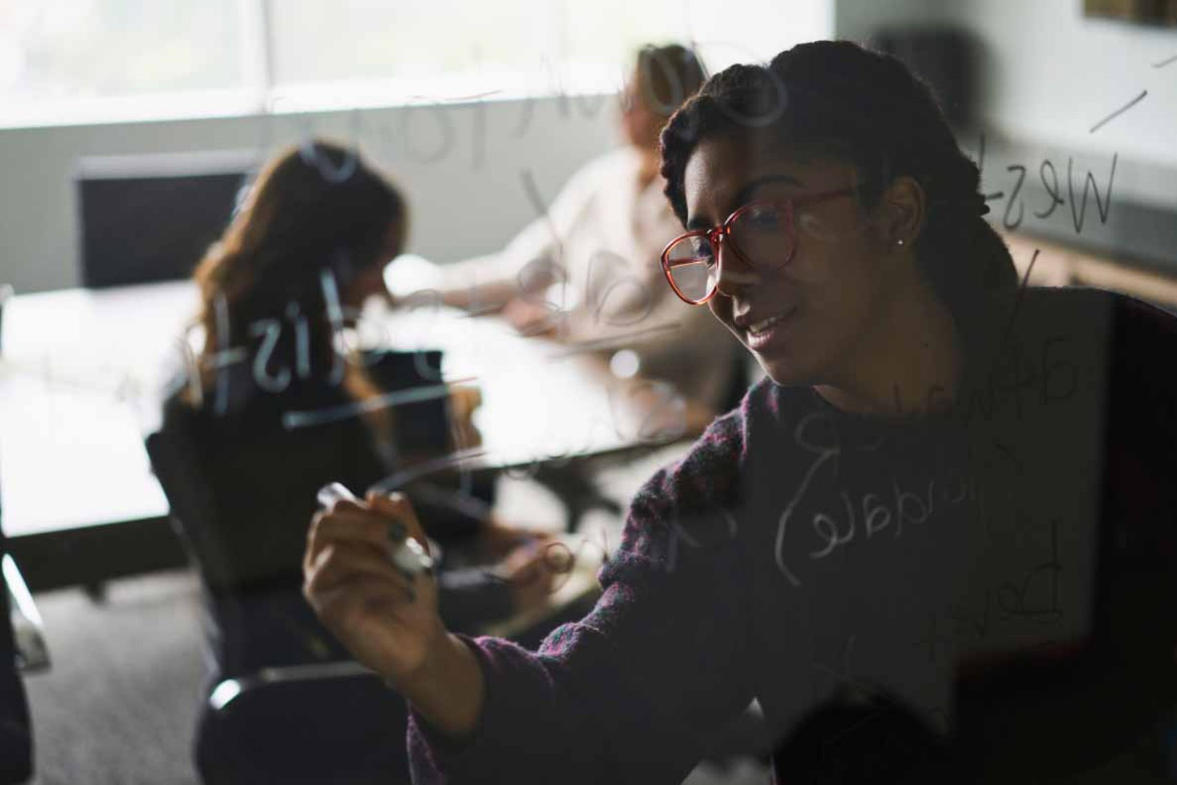 A woman writing something on a glass wall