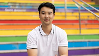 Man sitting in front of rainbow-colored stairs