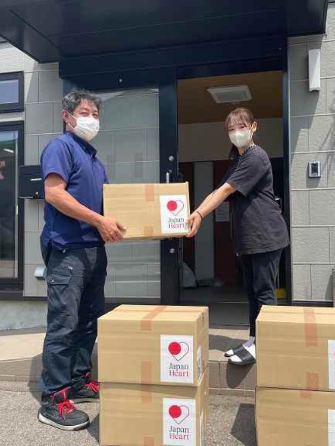 Two people with masks carrying boxes