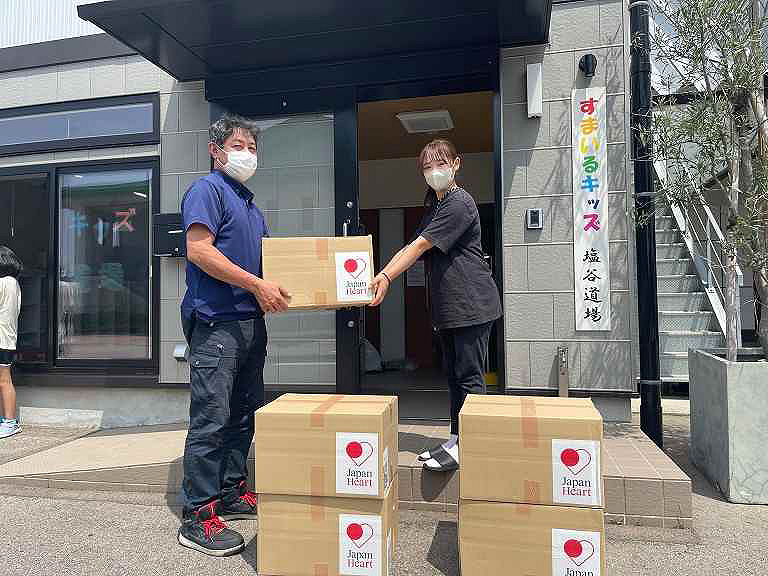 Two people with masks carrying boxes