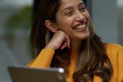 Smiling woman in yellow sweater with hand on her chin