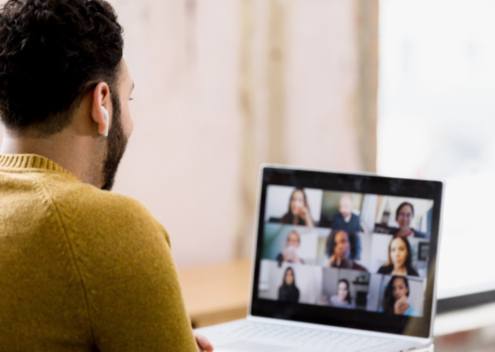A man wearing yellow sweater in a group meeting via online