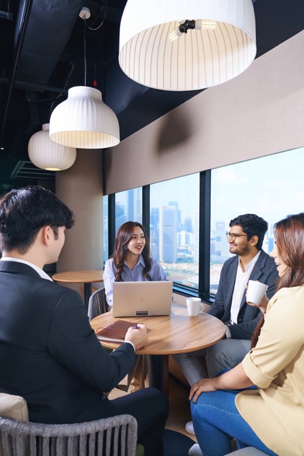 Four people having coffee and discussing in office