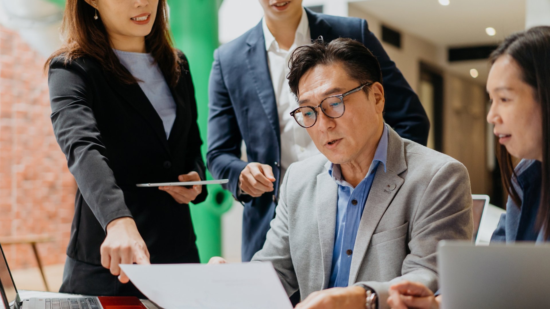 Image Of A Team Of Asian Business Professionals Meeting In Coworking Office. Business Leader Sharing Business Plan To His Employees In A Meeting.