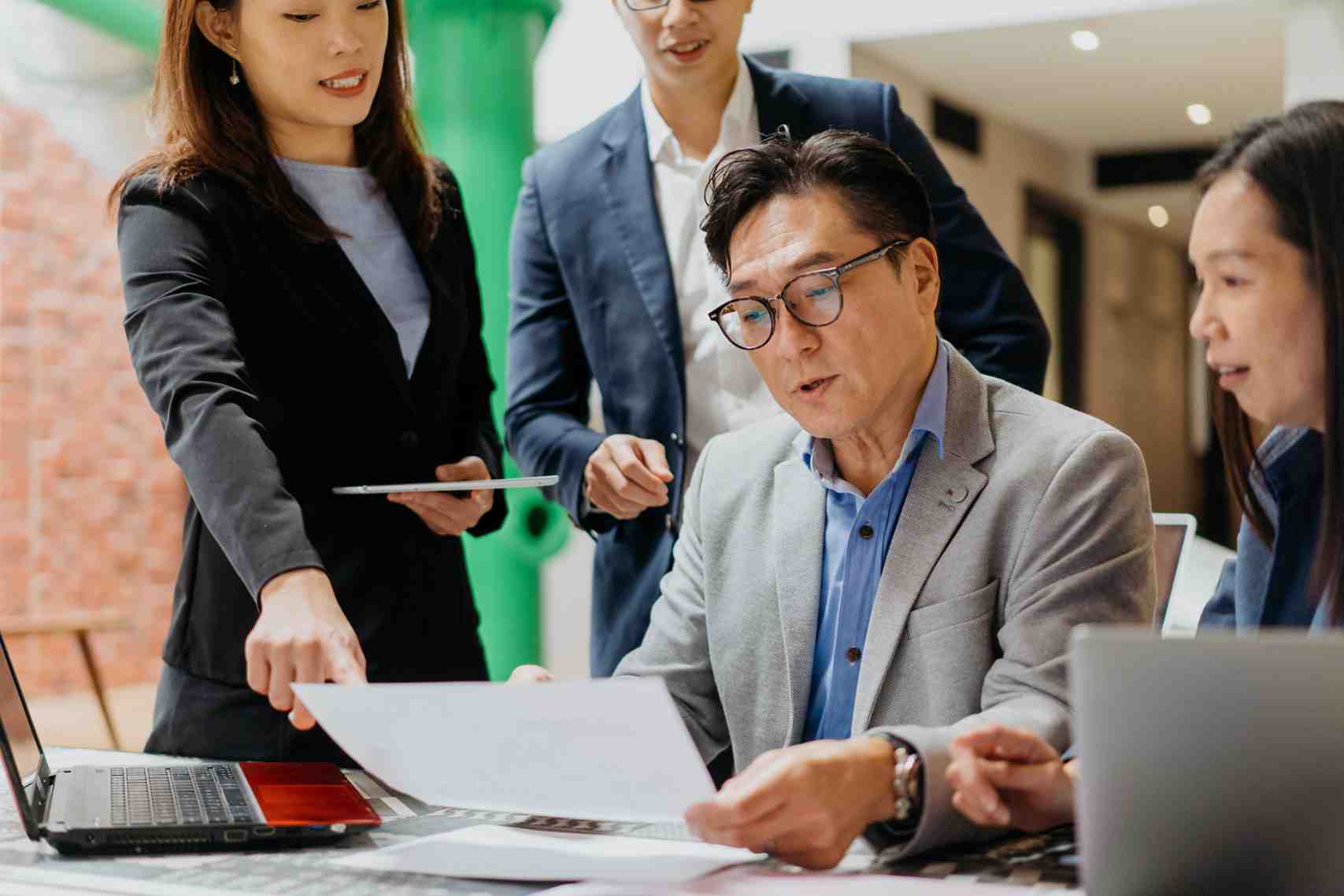 Image Of A Team Of Asian Business Professionals Meeting In Coworking Office. Business Leader Sharing Business Plan To His Employees In A Meeting.