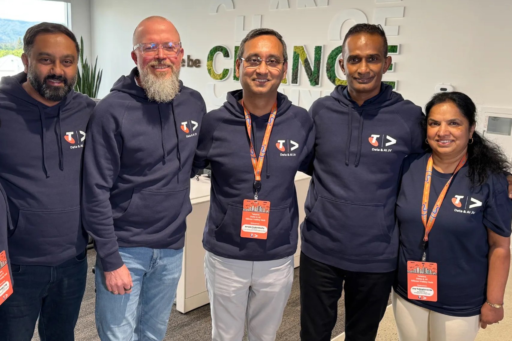 Group photo of Telstra–Accenture team members wearing branded hoodies during an onsite office engagement, reflecting collaboration and partnership culture.
