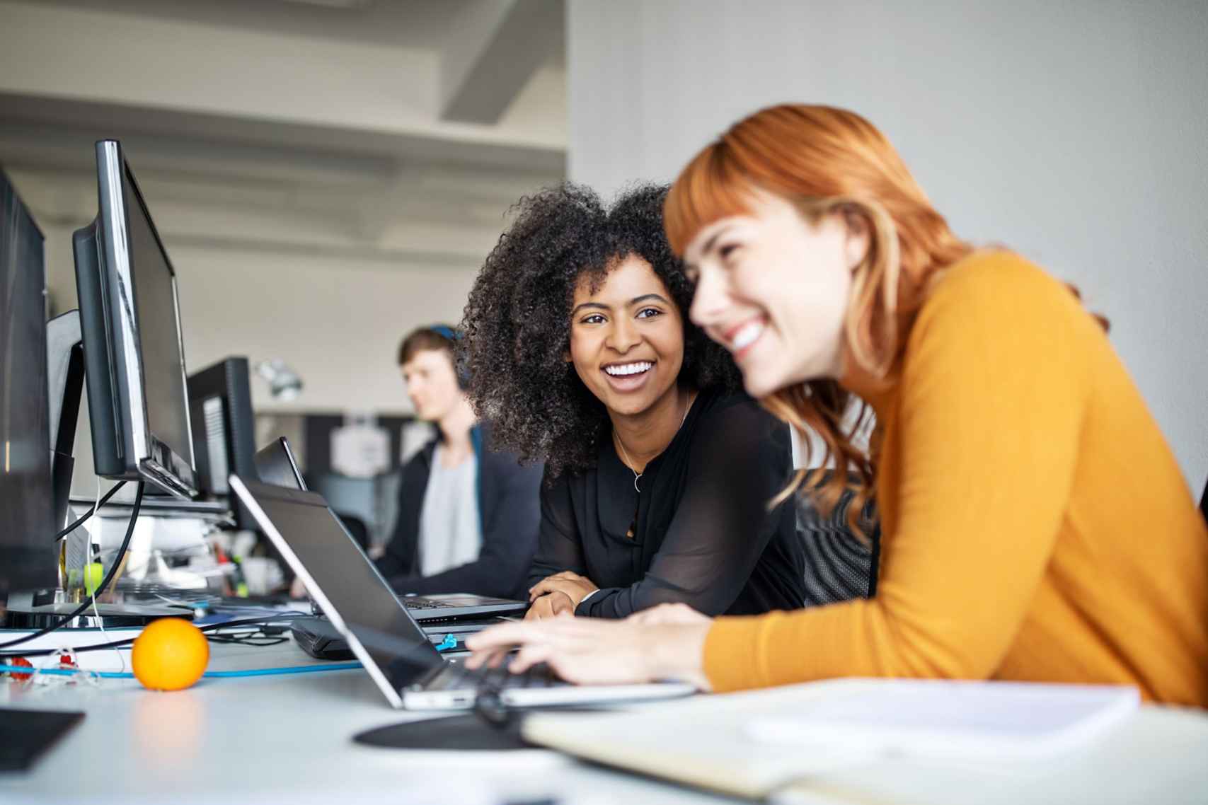 Two Woman Smiling While Working on Computer