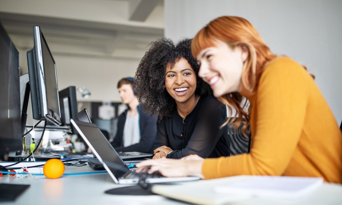 Two Woman Smiling While Working on Computer
