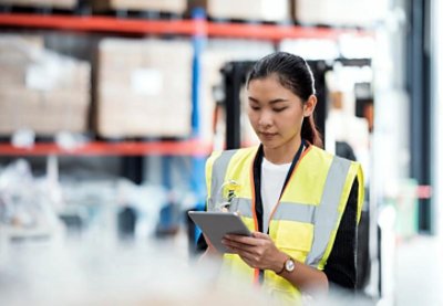 Woman counting stock with a tablet in a factory