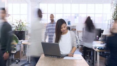 Woman Standing with Laptop on Busy Background