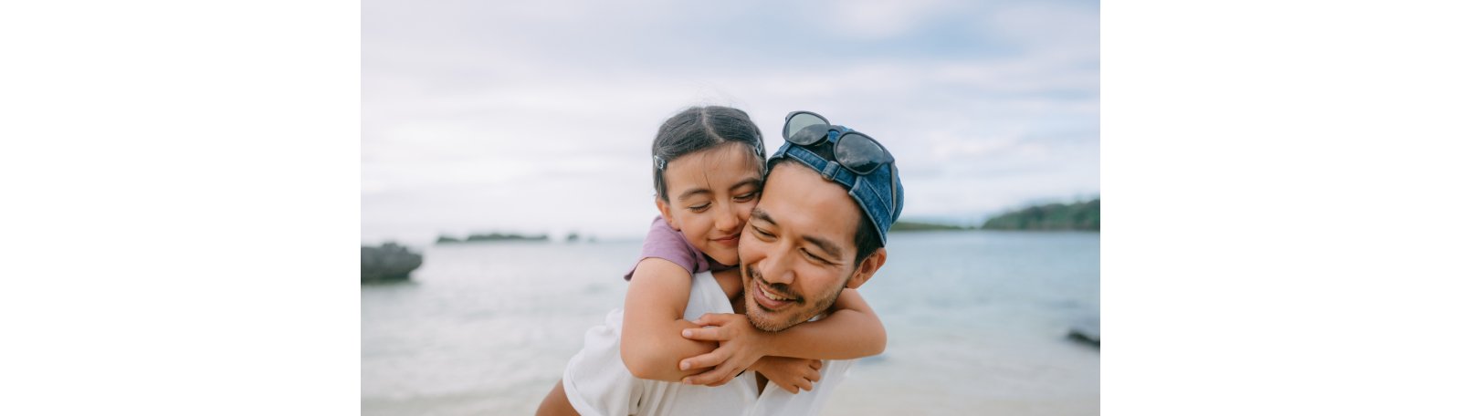 A father carrying his daughter on his back while in the beach