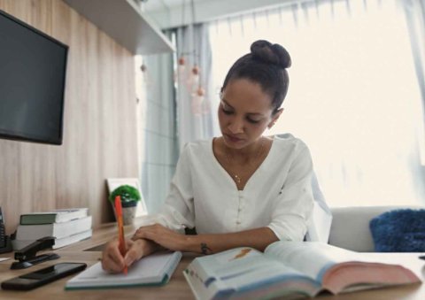 Women in a white clothes writing on a notebook