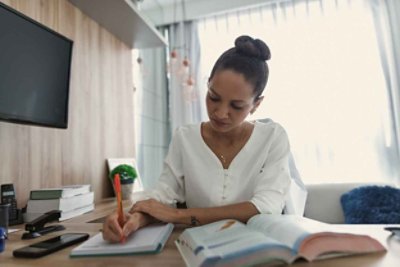 Women in a white clothes writing on a notebook