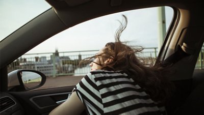 Young woman leaning out of car window