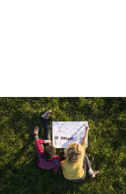 Top view of two kids sitting on a green field and drawing