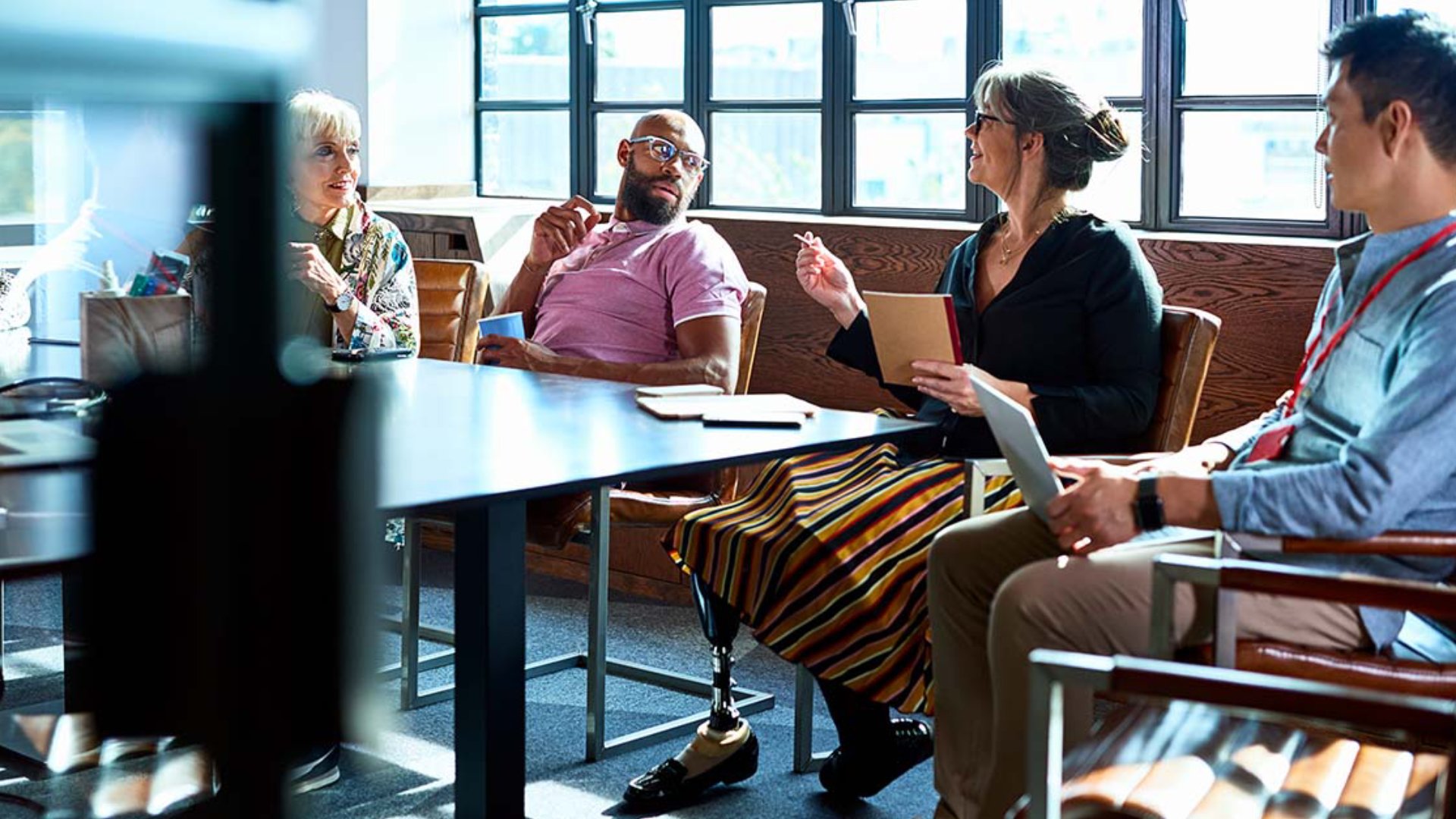 female businesswoman with prosthetic leg working with multi racial coworkers in business strategy review, leadership, knowledge, admiration