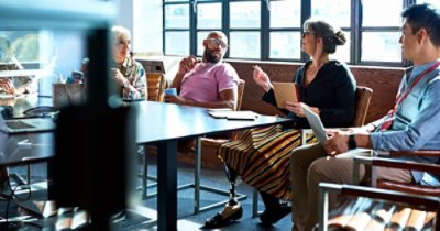 Senior female businesswoman with prosthetic leg working with multi racial coworkers in business strategy review, leadership, knowledge, admiration