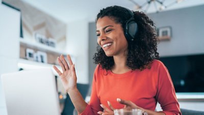 A girl wearing headphone smiling in front of the laptop