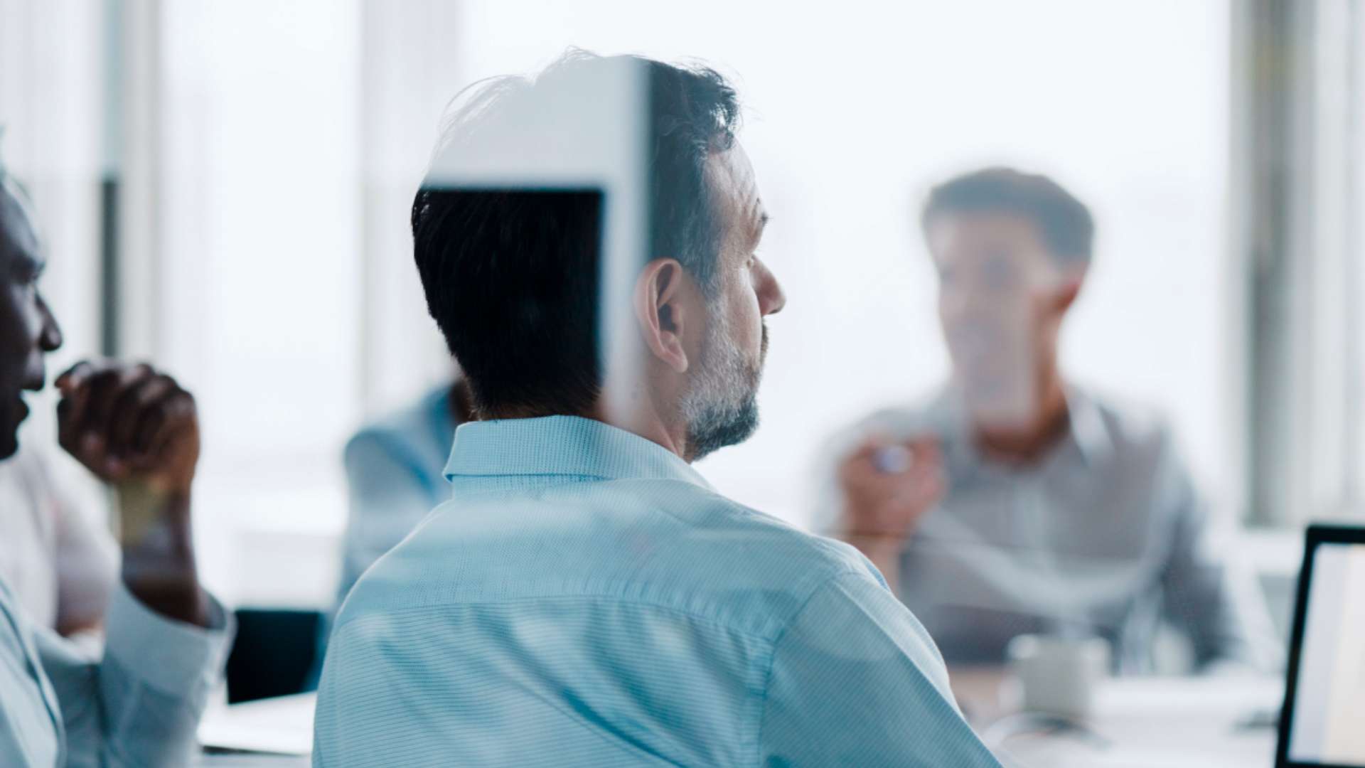 The backside of a business man listening to the meeting.