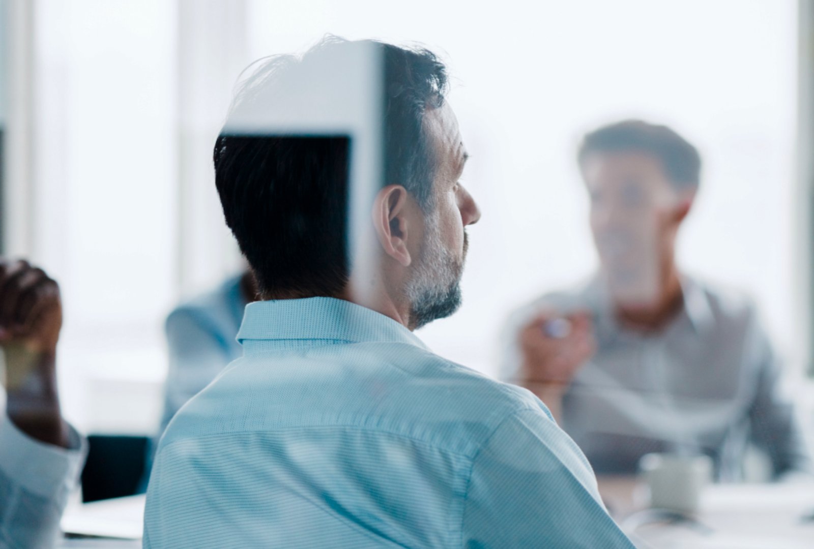 The backside of a business man listening to the meeting.