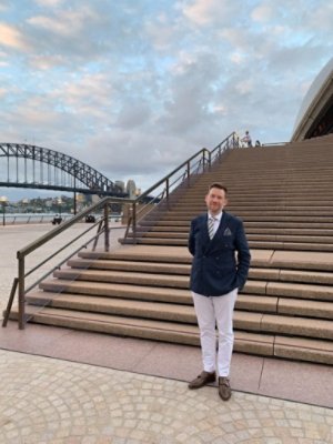 A man in a suit posing on the bottom of the stairs