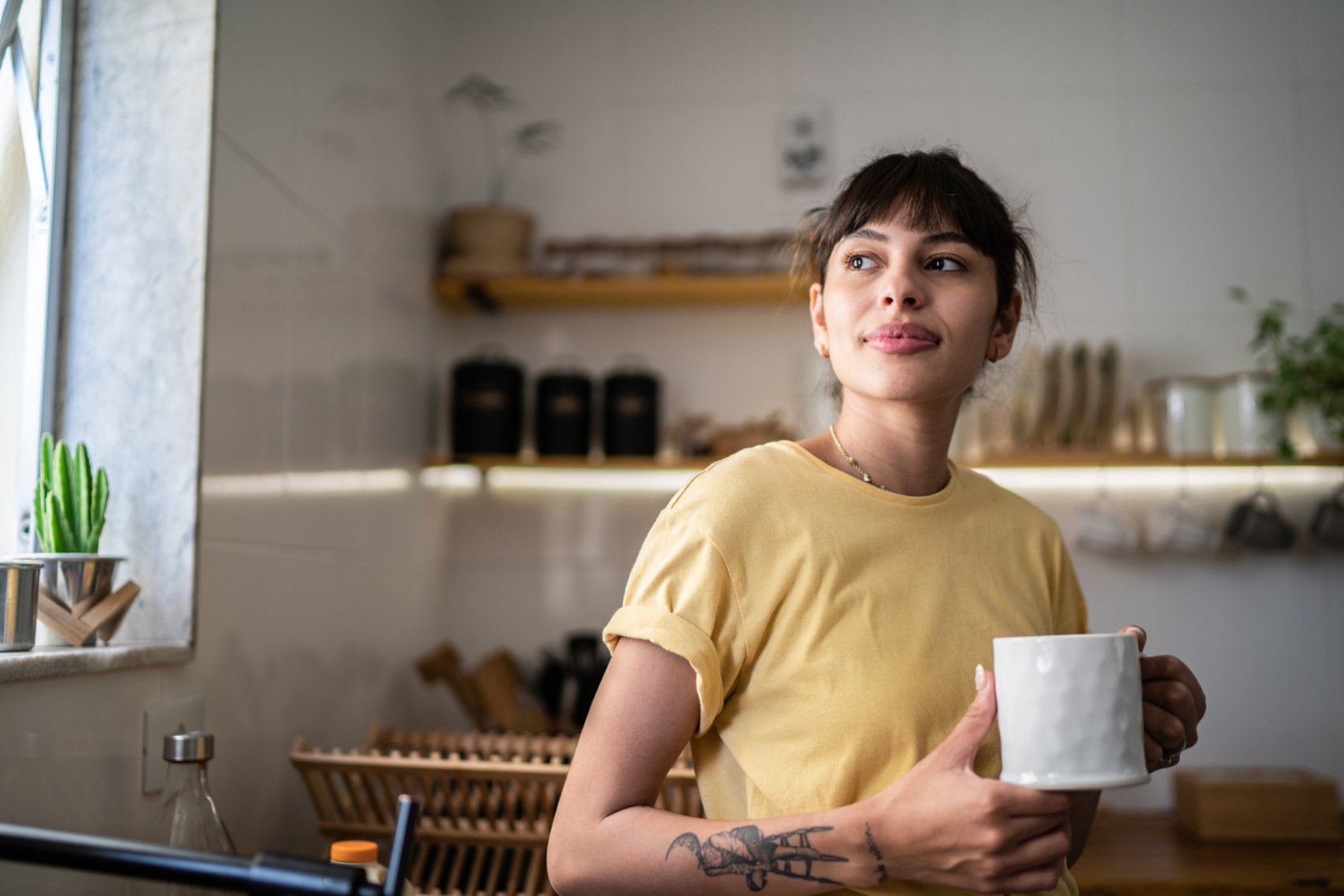 Woman wearing yellow shirt holding a mug.